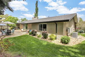 Expansive backyard featuring a large concrete patio, manicured lawn, and mature landscaping