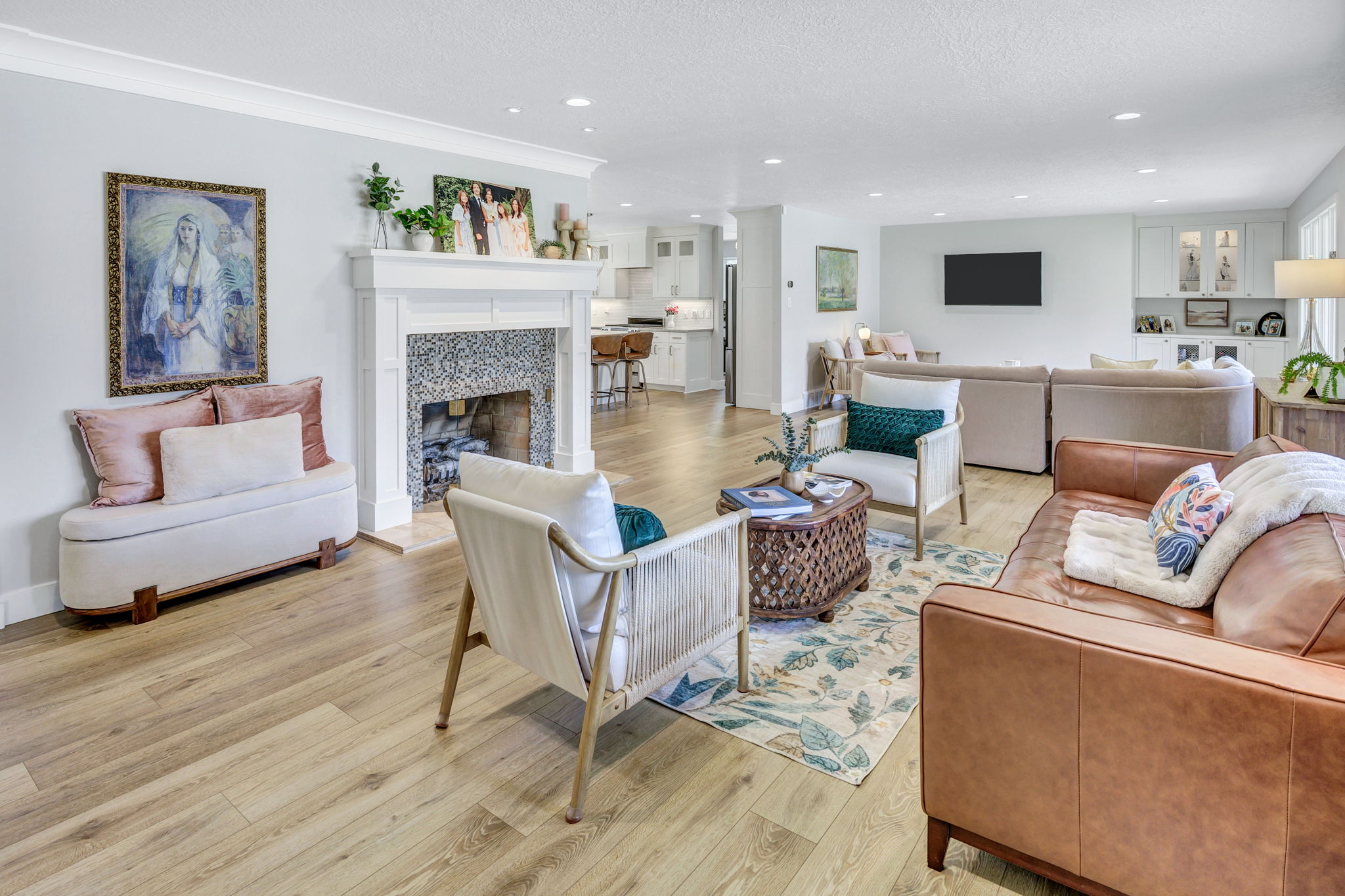 Bright living space featuring wood-finish flooring and a white fireplace with a mosaic tile surround