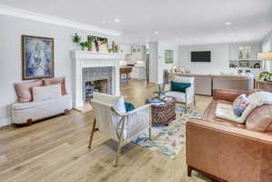 Bright living space featuring wood-finish flooring and a white fireplace with a mosaic tile surround