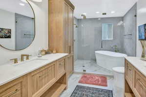 Bathroom featuring dual wood-finish vanities with white countertops and undermount sinks