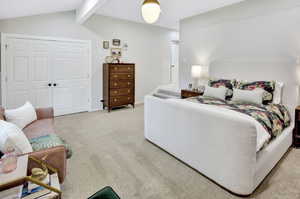 Carpeted bedroom with vaulted ceilings, recessed lighting, and a prominent pair of white panel doors