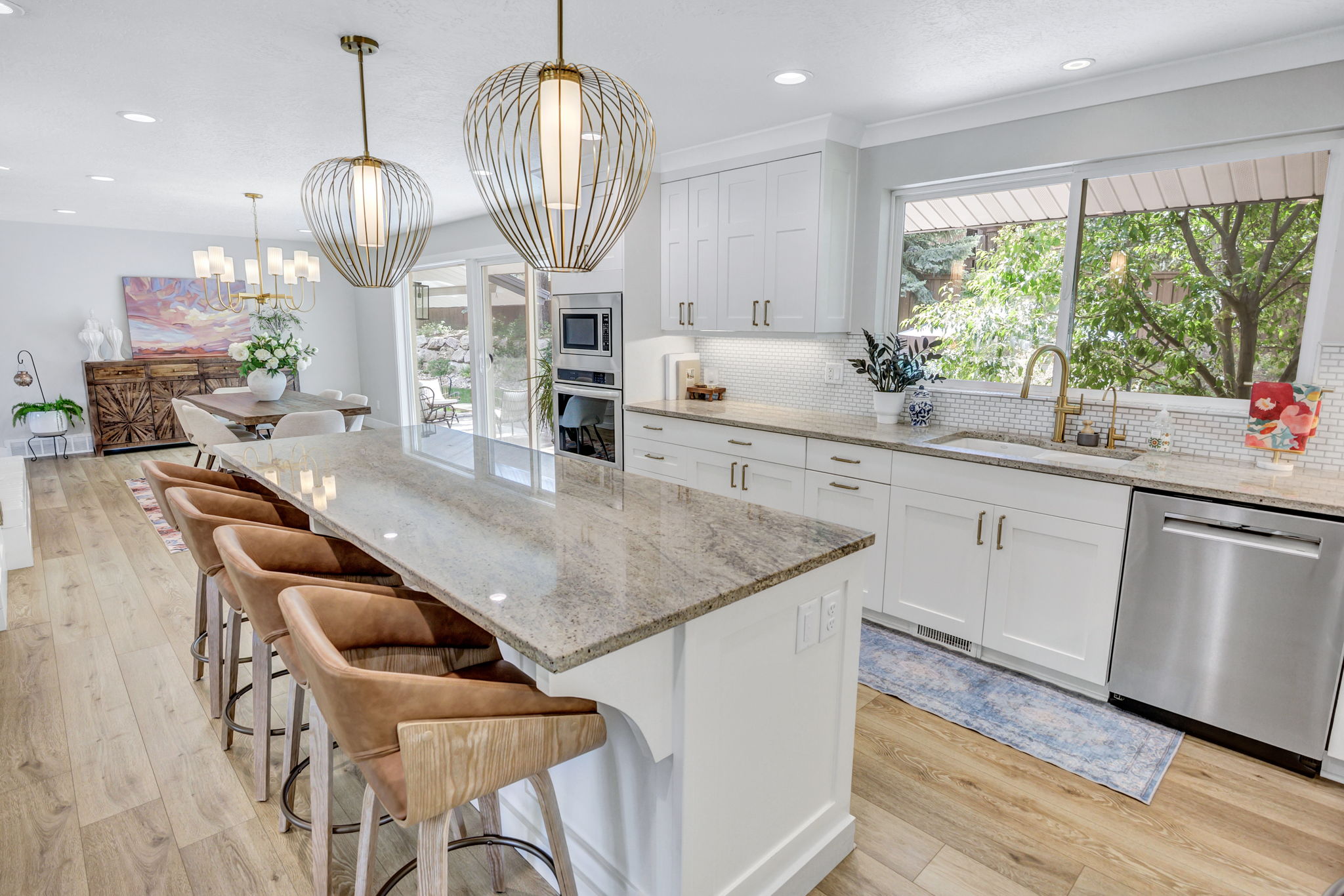 Open-concept kitchen featuring a large island with seating, pendant lighting, white cabinetry, a tiled backsplash, and stainless steel appliances