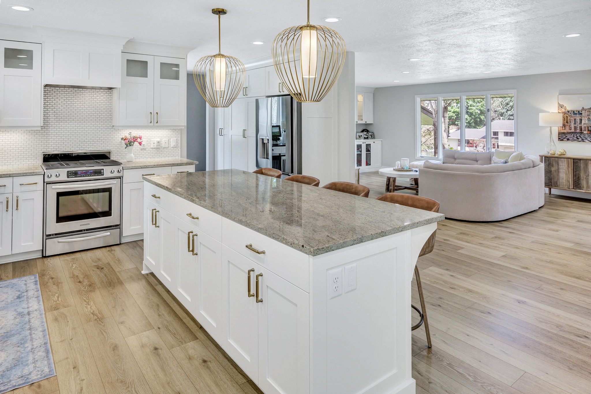 Kitchen featuring a large center island with a stone countertop, white shaker cabinetry with brass hardware, and wood-finish flooring