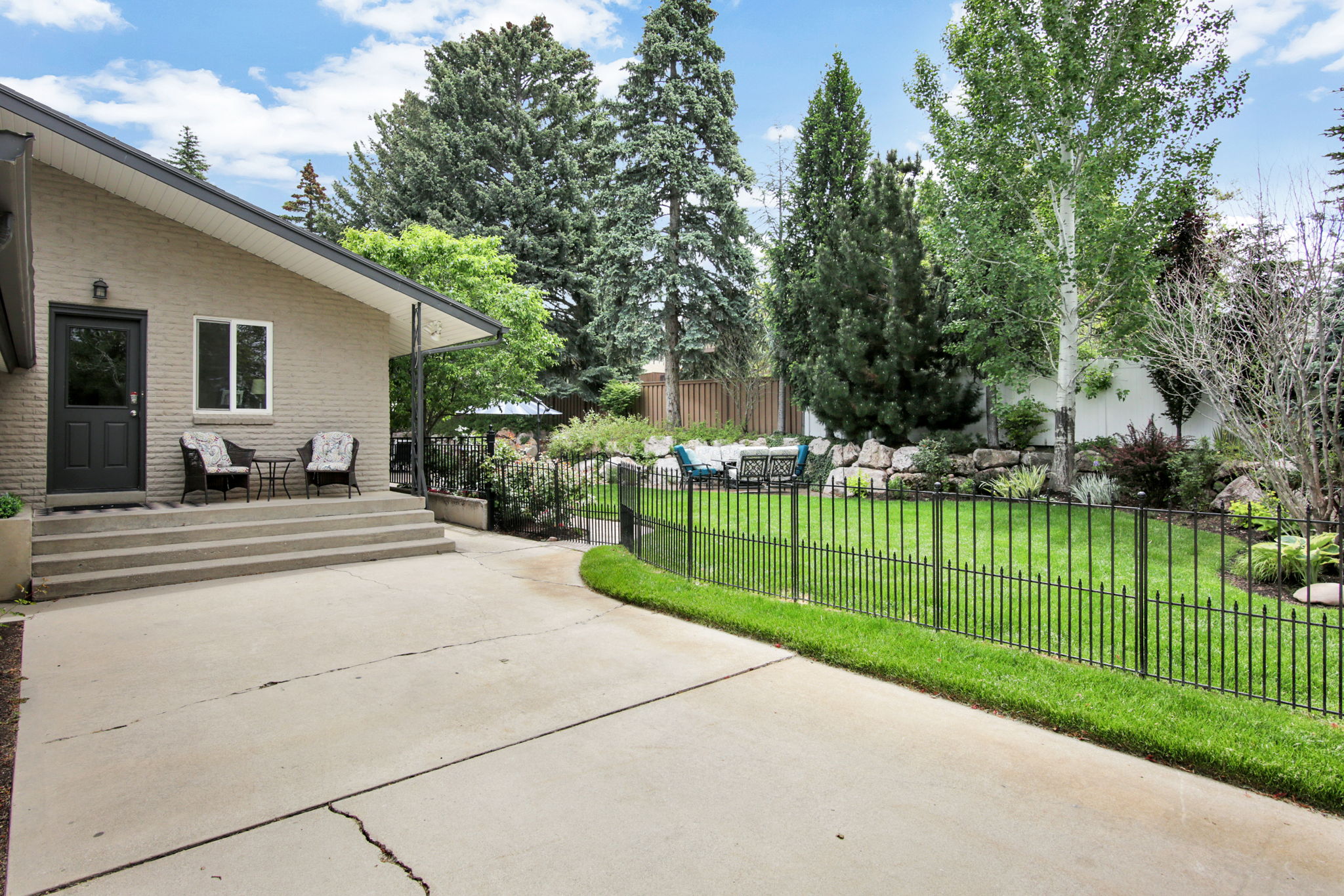 Rear exterior featuring a brick facade, covered patio, and concrete steps