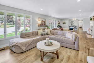Living area featuring expansive windows, recessed lighting, wood-finish flooring, and a white fireplace with a decorative mantel