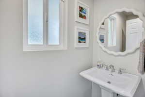 Pedestal sink with chrome-finish faucet and white scalloped mirror