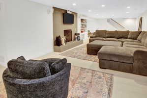 Recreational room featuring a fireplace with a tile surround and hearth, recessed lighting, built-in shelving, and carpet flooring