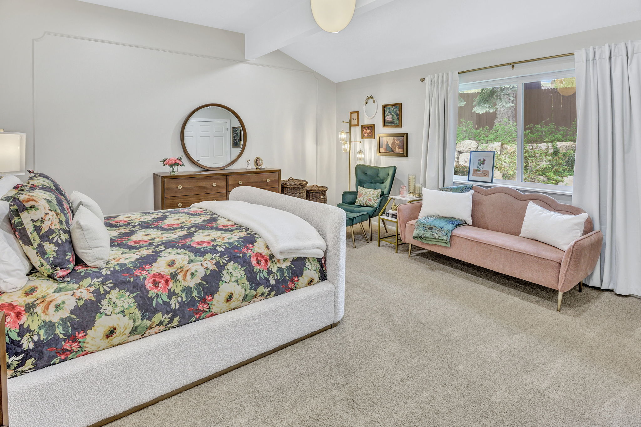 Spacious room featuring vaulted ceilings, ample natural light from a large window, light-toned carpeting, and a built-in wall molding accent
