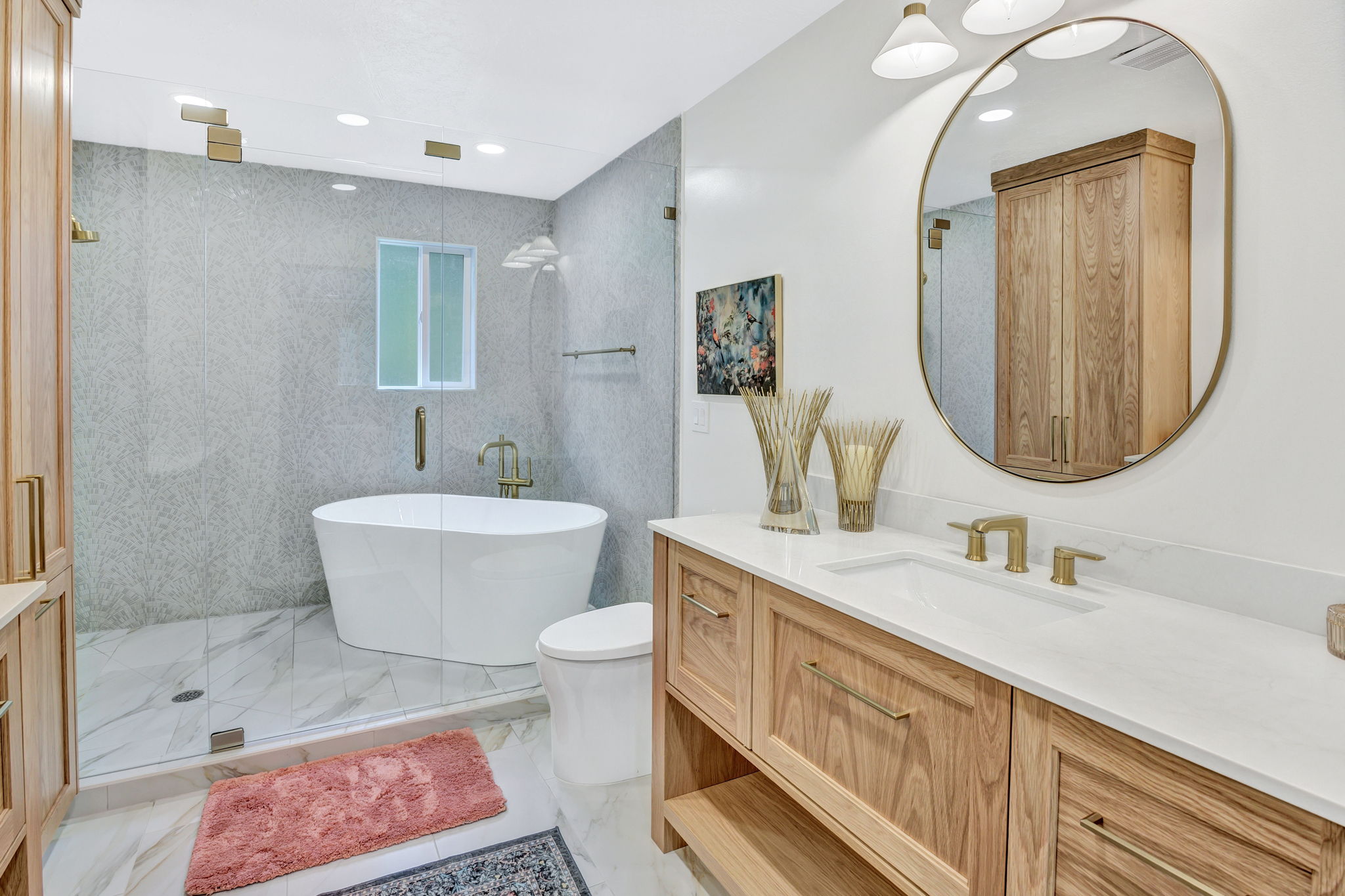 Spacious bathroom featuring a freestanding soaking tub, a walk-in shower with glass enclosure, a dual shower system, a wood-finish vanity with an integrated sink and gold-tone fixtures, and large-format tile flooring