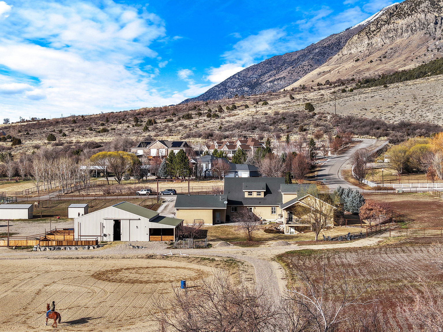 Expansive property featuring a tan exterior residence, a large barn, and a circular riding arena