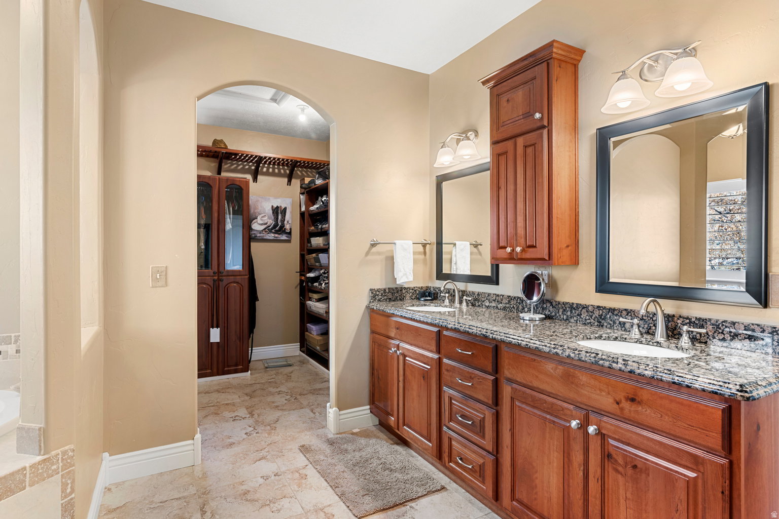 Double vanity featuring wood cabinetry, granite countertops, and two undermount sinks