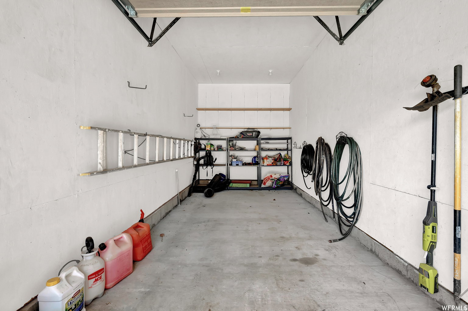 Attached garage space featuring concrete flooring, white painted walls, and overhead garage door tracks
