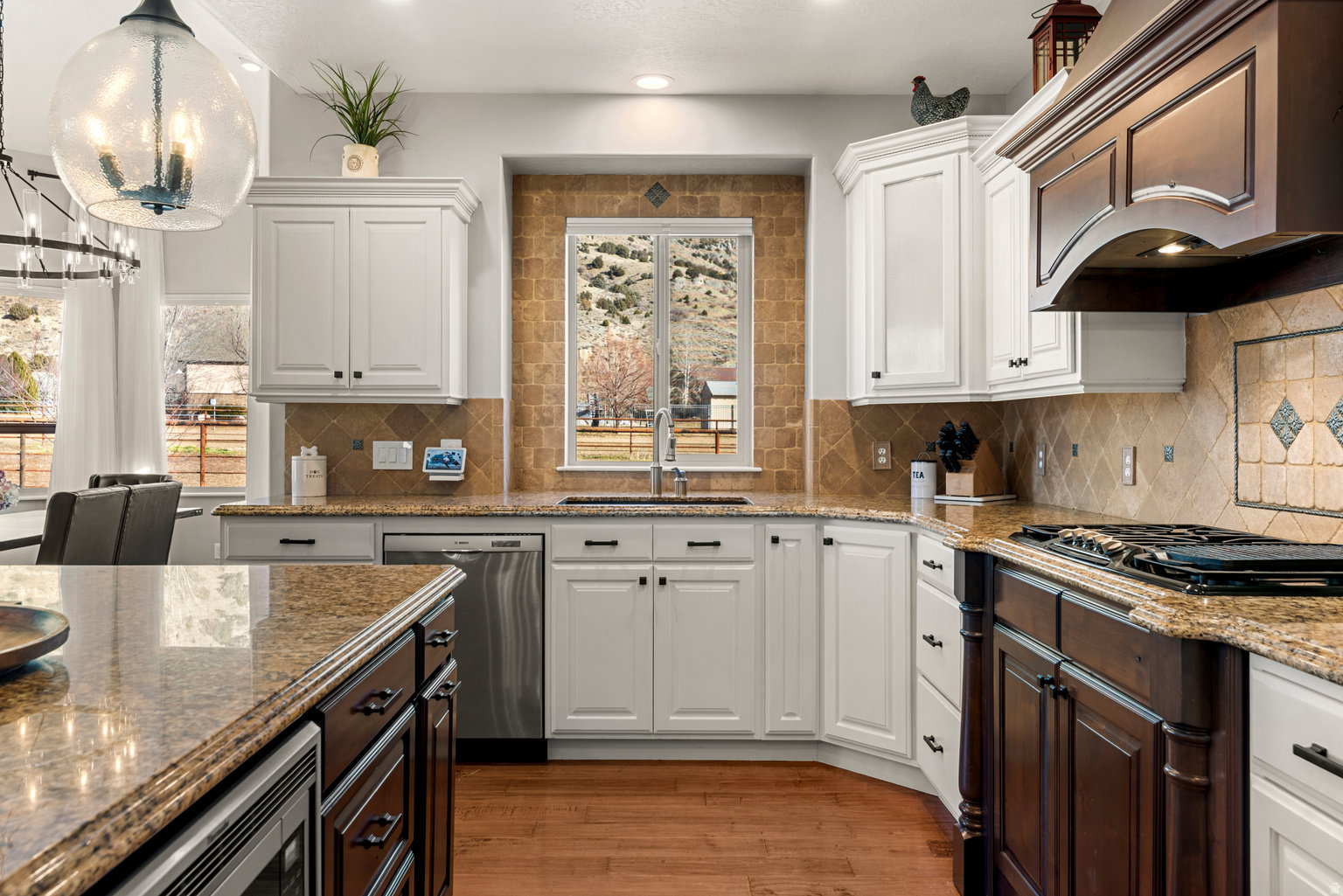 Kitchen featuring granite countertops, wood-finish flooring, two-tone cabinetry, stainless steel appliances, and a tile backsplash