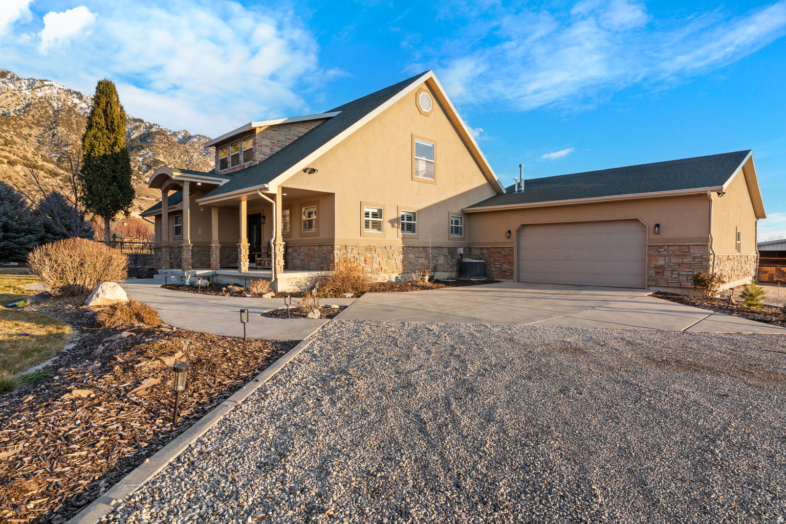 Stucco exterior with stone accenting, covered front porch, and an attached two-car garage