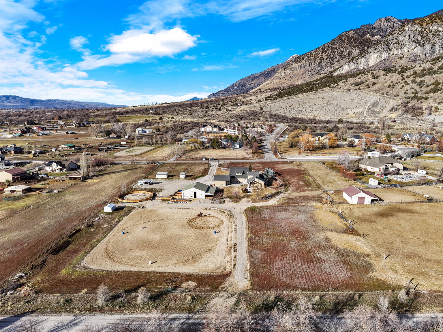 Expansive property featuring a main residence, two outbuildings, an agricultural field, and a circular riding arena