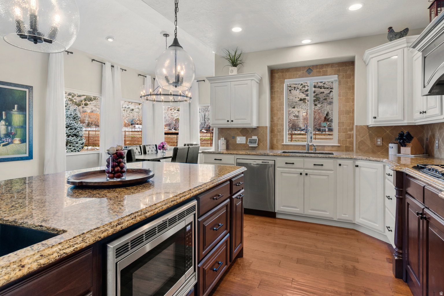 Gourmet kitchen with light and dark cabinetry, granite countertops, stainless steel appliances, and wood-finish flooring