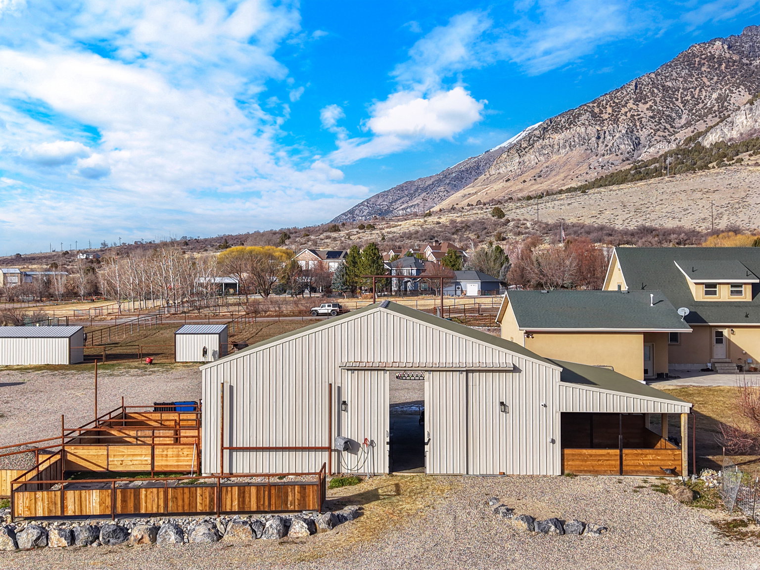 Metal-sided barn structure featuring a gabled roof, sliding barn door, and an attached lean-to with wood paneling