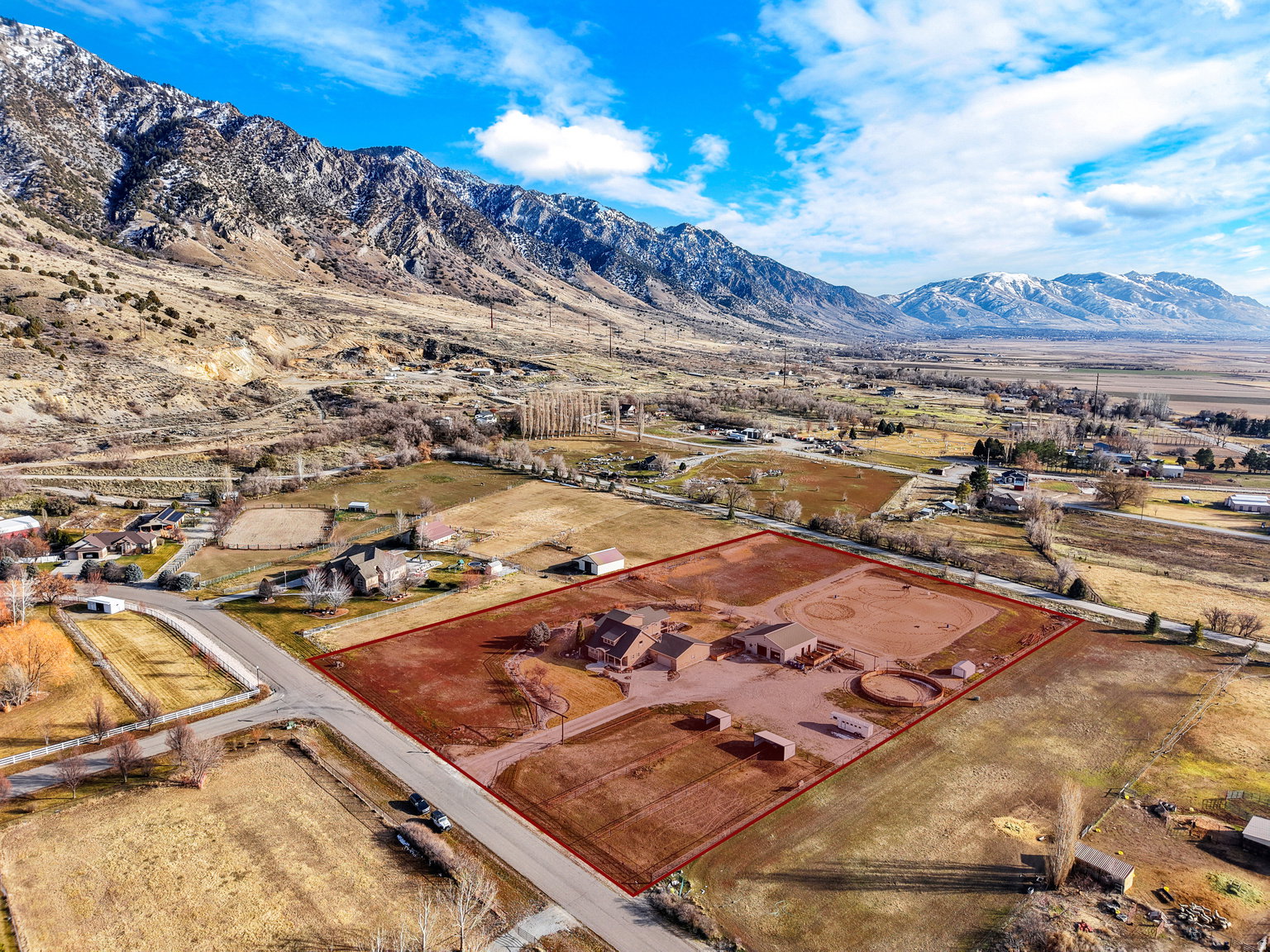 Expansive property outlined by a red boundary, featuring a residence with multiple outbuildings