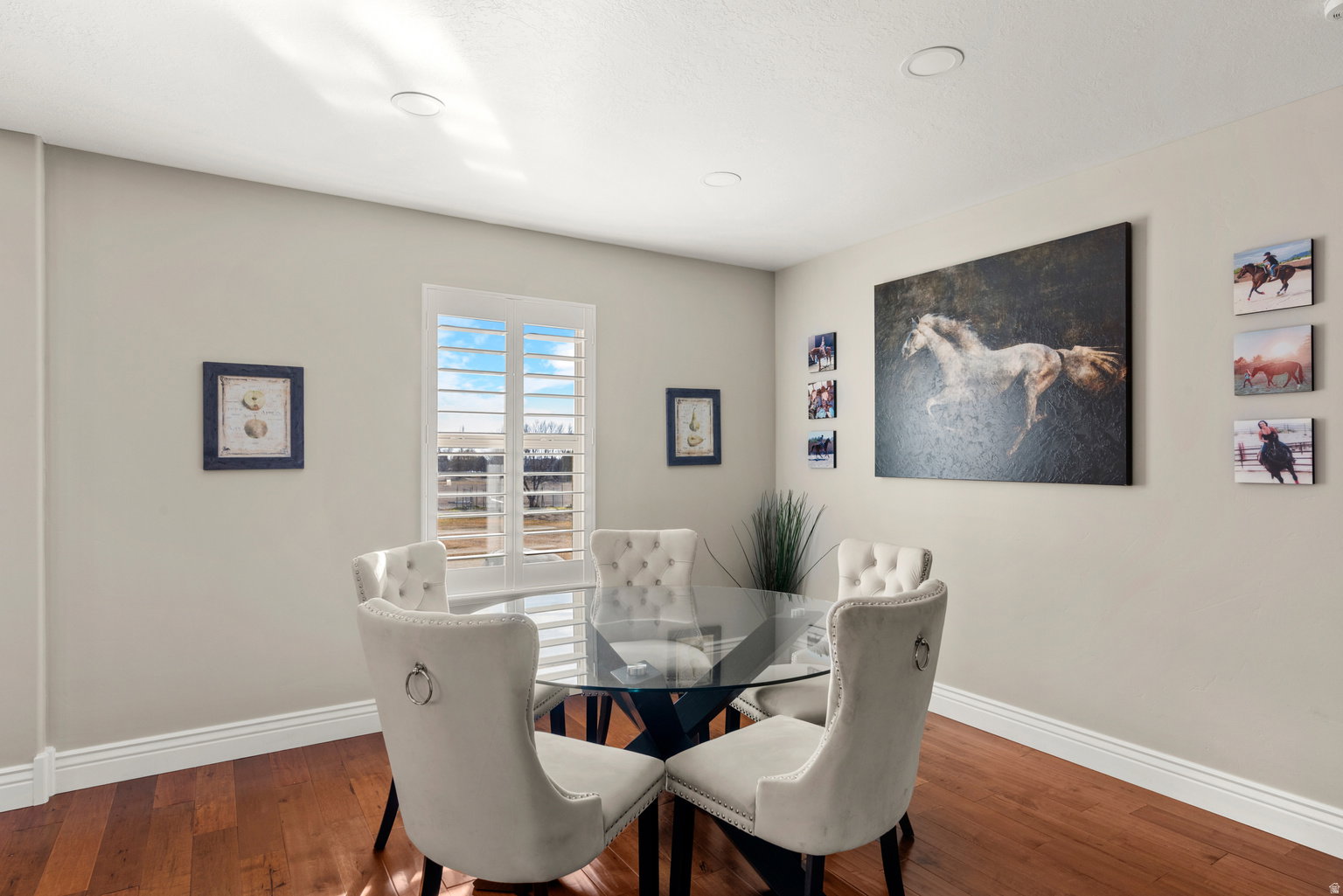 Hardwood flooring with white baseboards, recessed ceiling lighting, and a window with plantation shutters