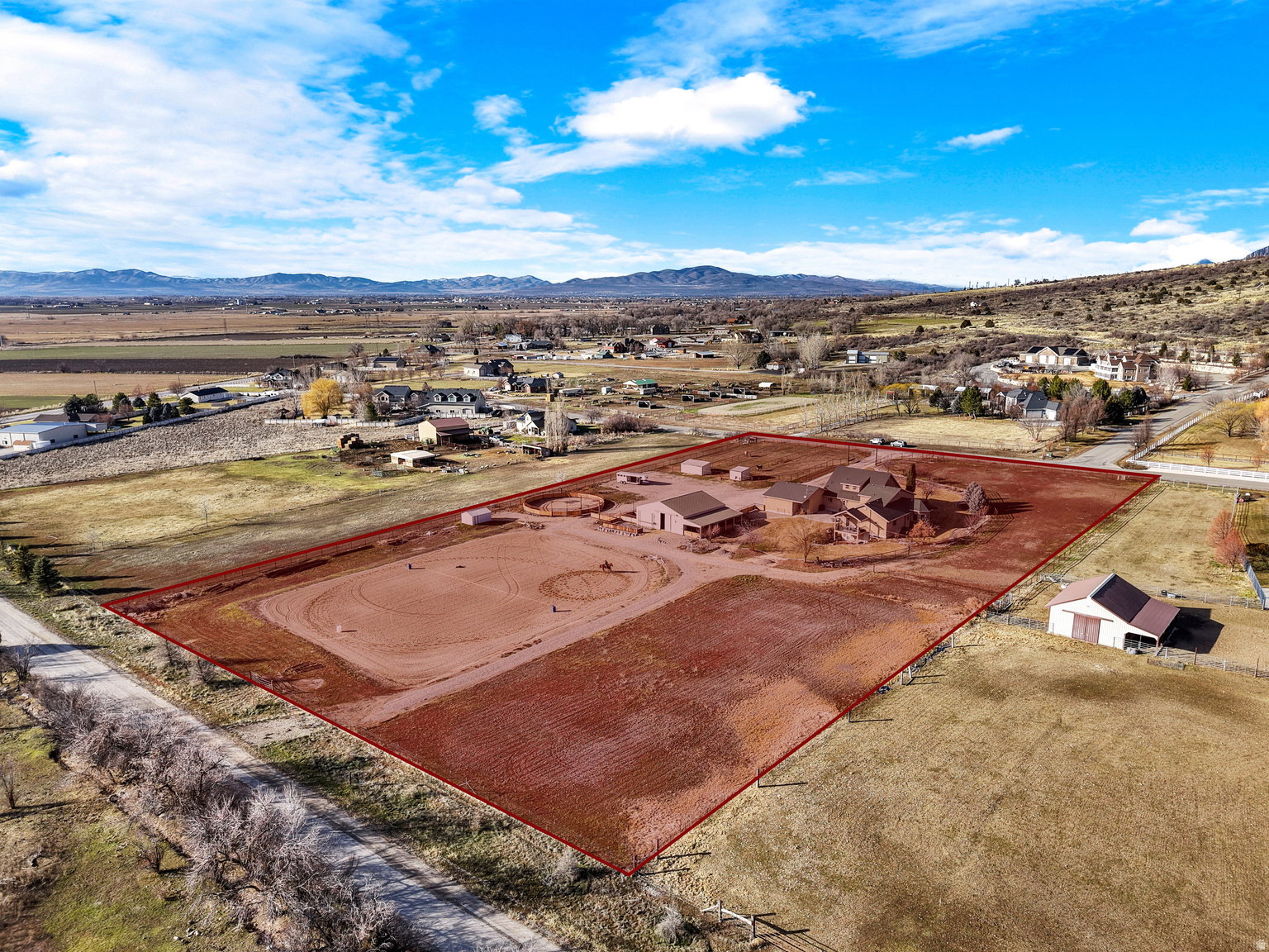 Expansive rural property featuring multiple structures, an equestrian arena, and surrounding open land