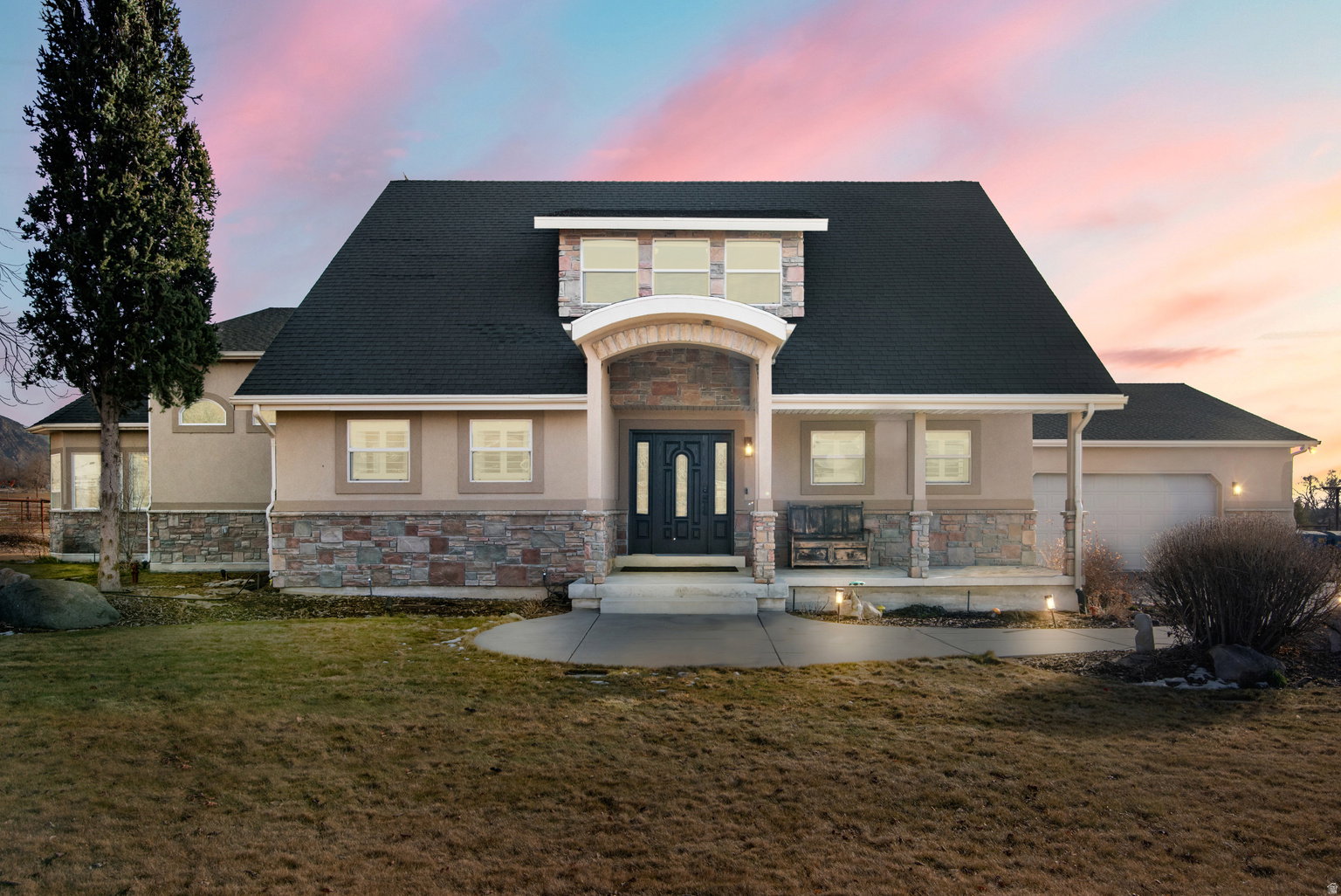 Stucco and stone facade with a dark asphalt shingle roof