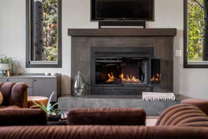 Contemporary fireplace featuring a dark wood-finish mantel and hearth, flanked by two framed windows