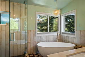 Freestanding soaking tub with a floor-mounted faucet, complemented by wood-finish wall paneling and hexagonal floor tiling