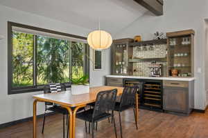 Built-in wet bar featuring a subway tile backsplash, glass-front cabinetry, and two under-counter beverage refrigerators