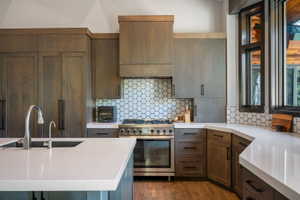 Gourmet kitchen featuring a built-in gas range, integrated refrigerator, custom wood cabinetry, hexagon tile backsplash, and quartz countertops with an undermount sink