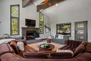 Vaulted ceilings with exposed beams complement the modern fireplace featuring a dark wood mantle and hearth