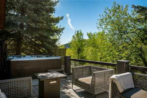 Expansive outdoor deck featuring a built-in hot tub, dark wood-finish railing, and a slatted privacy screen