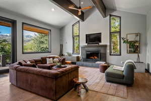Living area featuring a vaulted ceiling with exposed beams and a ceiling fan