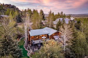 Wood-sided residence featuring a metal roof, an expansive outdoor deck, and a multi-level putting green