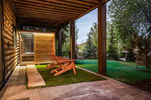 Covered patio area featuring a built-in outdoor sauna with a glass and wood-panel door
