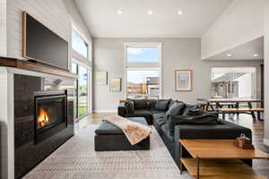 Great room featuring a built-in fireplace with a dark stone surround and wood mantel, vaulted ceilings, recessed lighting, and expansive windows