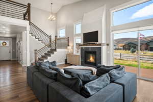 Great room featuring wood-finish flooring, a two-story vaulted ceiling, and a fireplace with a shiplap surround and dark stone hearth