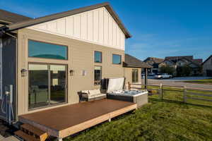 Rear exterior featuring a spacious wood-finish deck with built-in spa