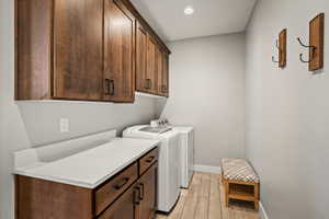 Dedicated laundry space featuring extensive wooden cabinetry, light-toned countertops, and wood-finish flooring