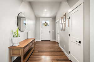Entryway featuring wood-finish flooring, vaulted ceilings, and white trim