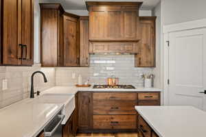 Kitchen featuring rich wood cabinetry with black hardware, white subway tile backsplash, and light-colored countertops