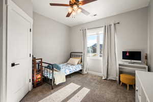 Room featuring neutral wall tones, textured carpeting, and a ceiling fan with integrated lighting