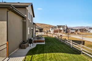 Rear exterior featuring a wood deck, concrete patio, and a manicured lawn