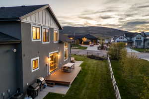 Rear exterior featuring a multi-level wood-finish deck, sliding glass door, and a manicured lawn