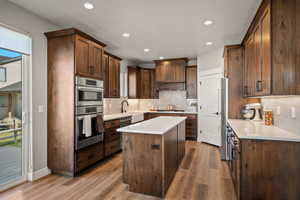 Spacious kitchen featuring wood-finish cabinetry, a central island with white countertop, and stainless steel built-in appliances