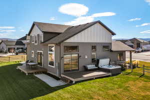 Rear exterior featuring multiple decks, a hot tub, and a spacious grassy yard
