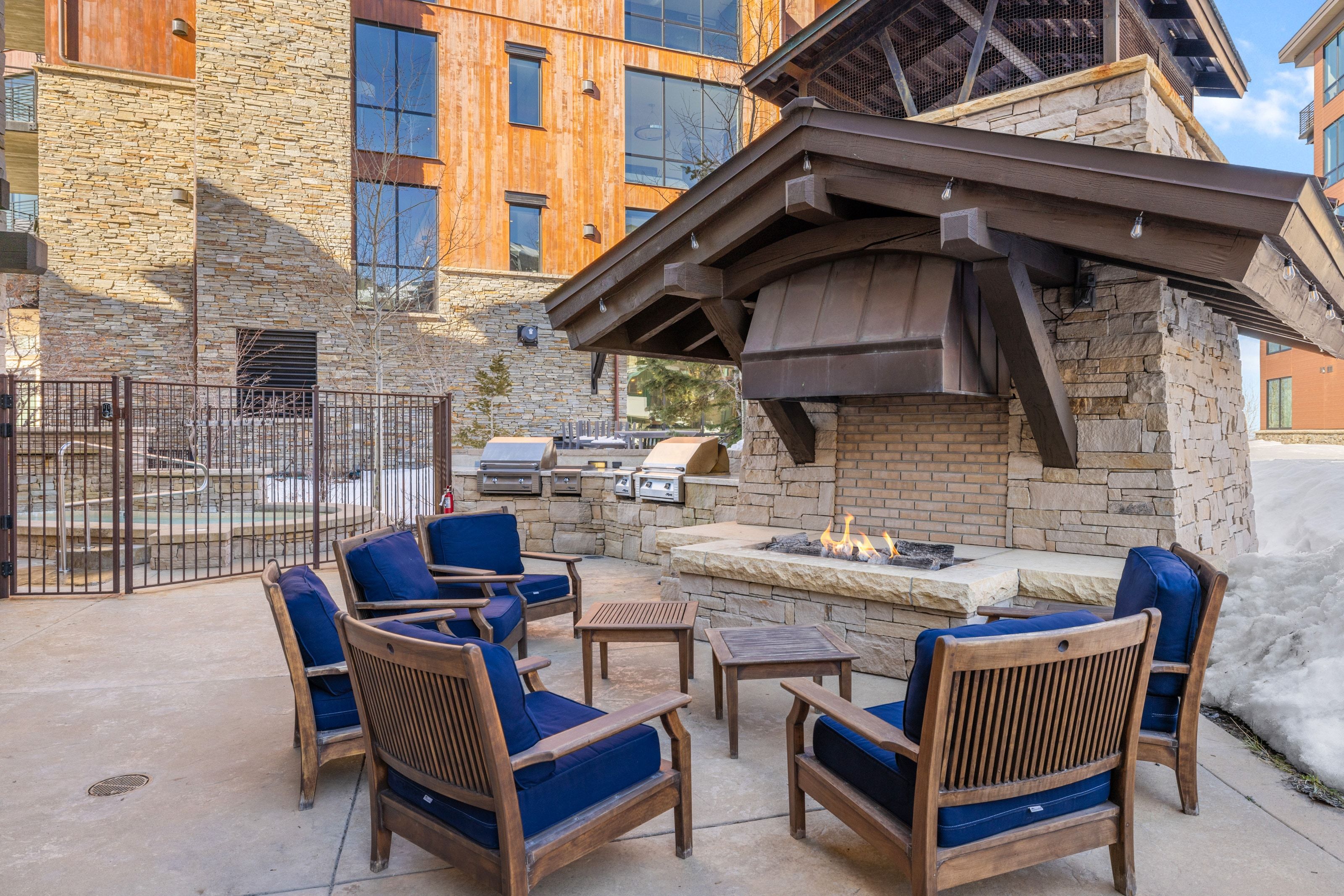 Outdoor patio featuring a stone-clad fireplace with a substantial hearth, an overhead canopy, and built-in grills