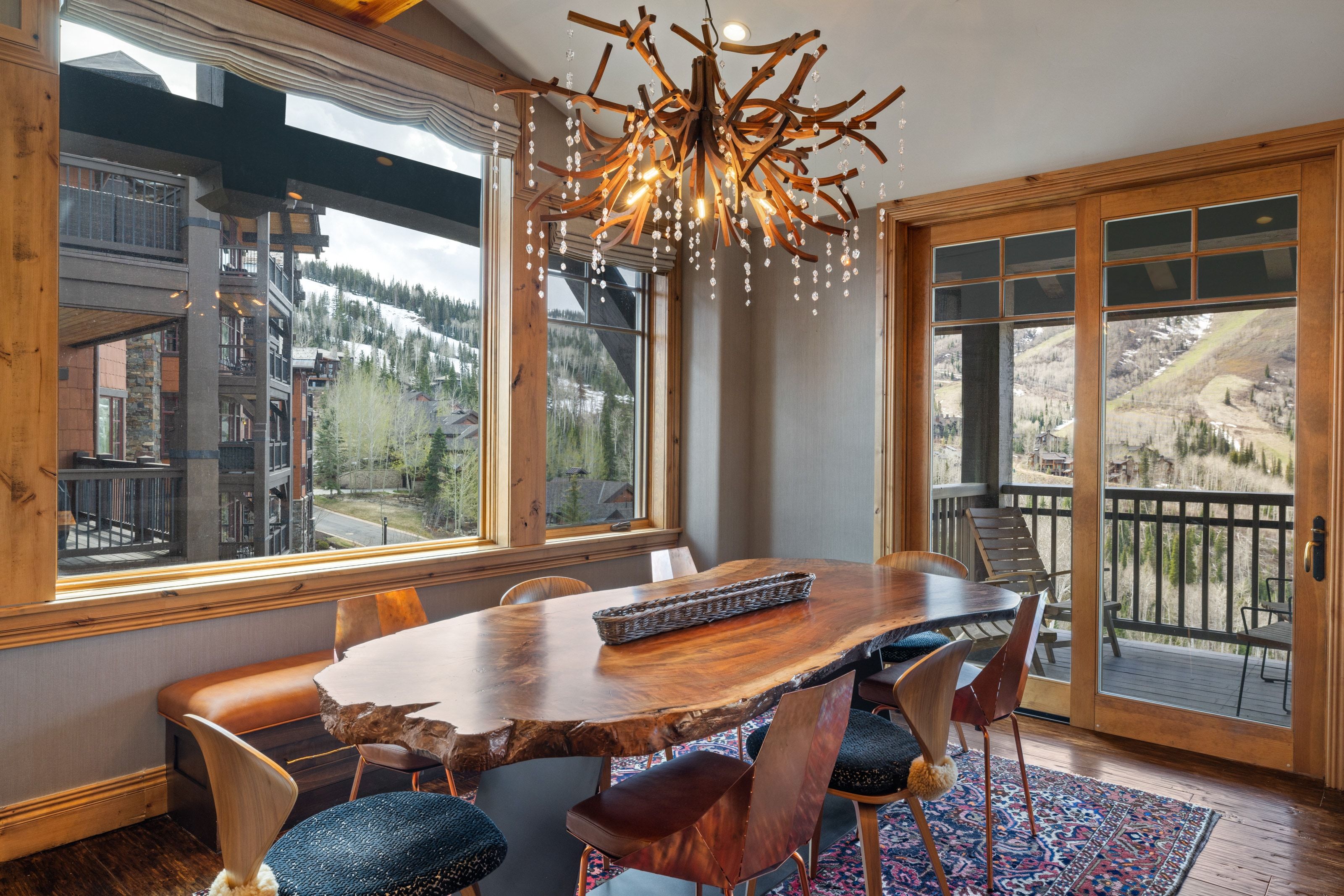 Dining area featuring a live-edge wood slab table, a branch-inspired chandelier with crystal accents, and wood-finish flooring