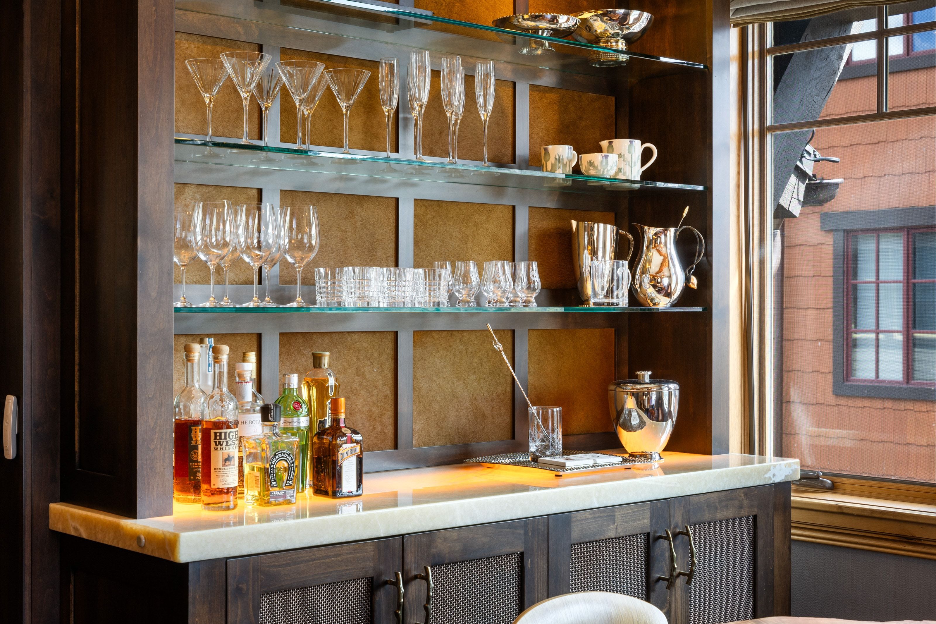 Custom built-in bar featuring dark wood cabinetry with textured inserts and bronze hardware