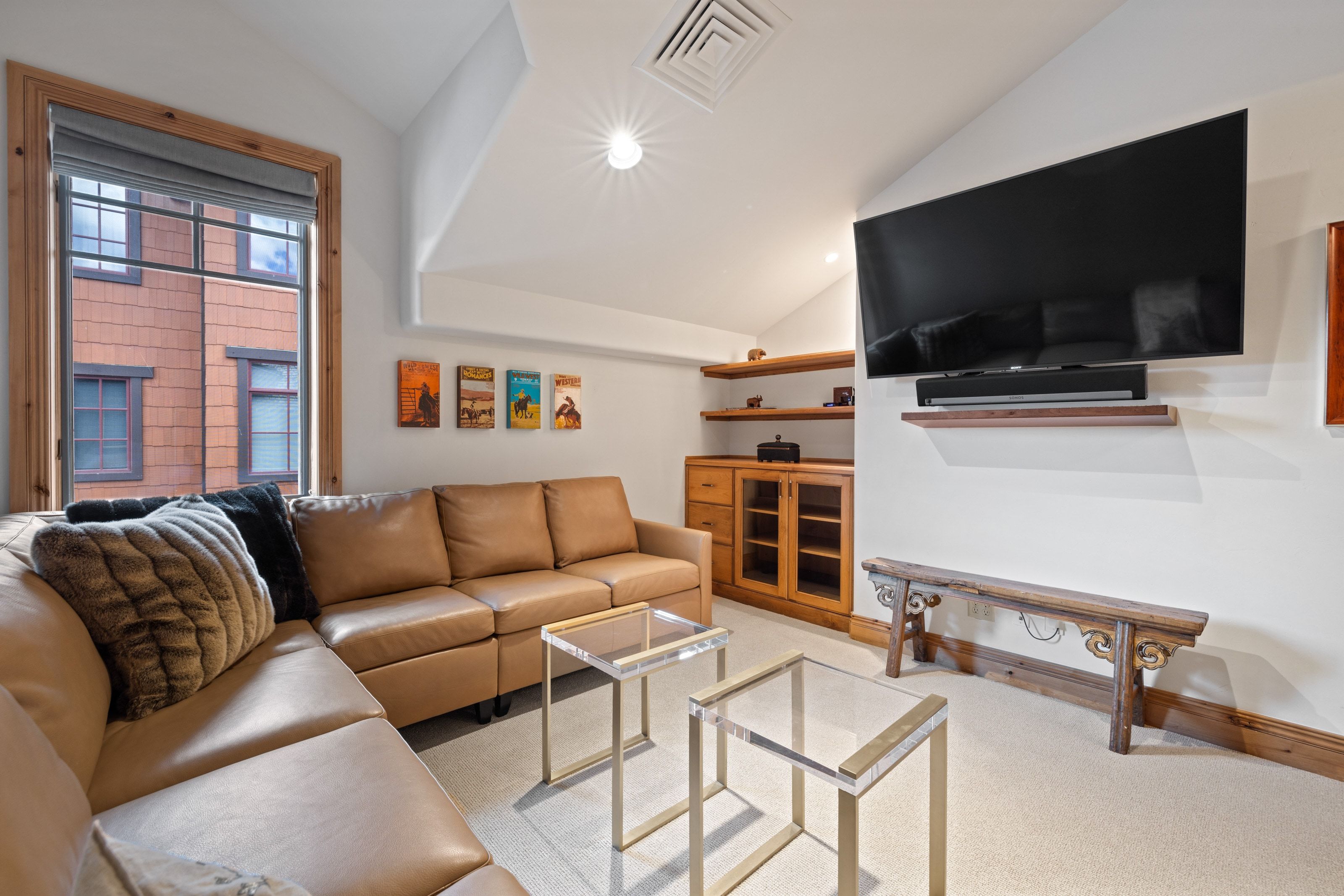 Media room featuring a wall-mounted television, built-in wooden cabinetry with glass doors, and recessed lighting