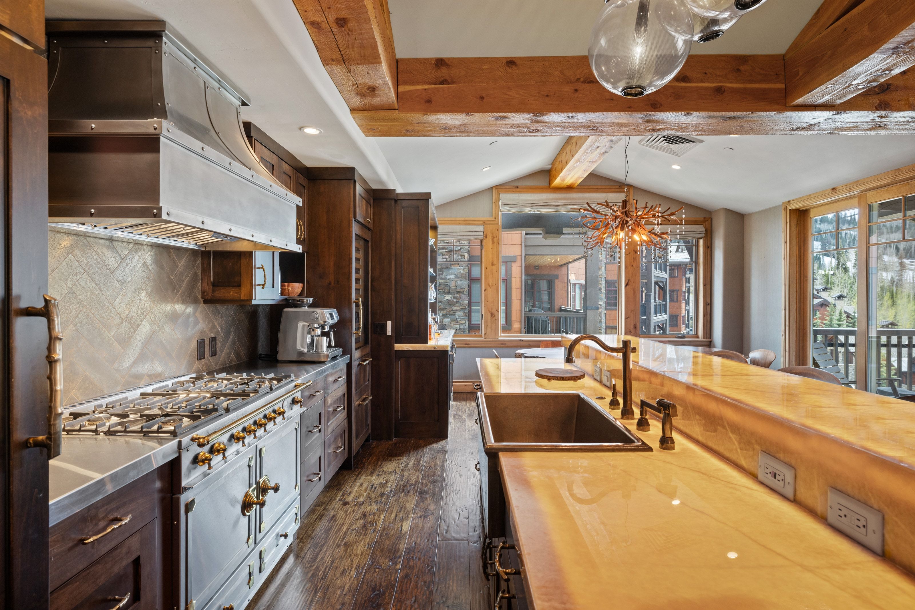 Gourmet kitchen featuring a professional-grade range with a custom metal hood, dark wood cabinetry, wood-finish flooring, and a unique illuminated countertop